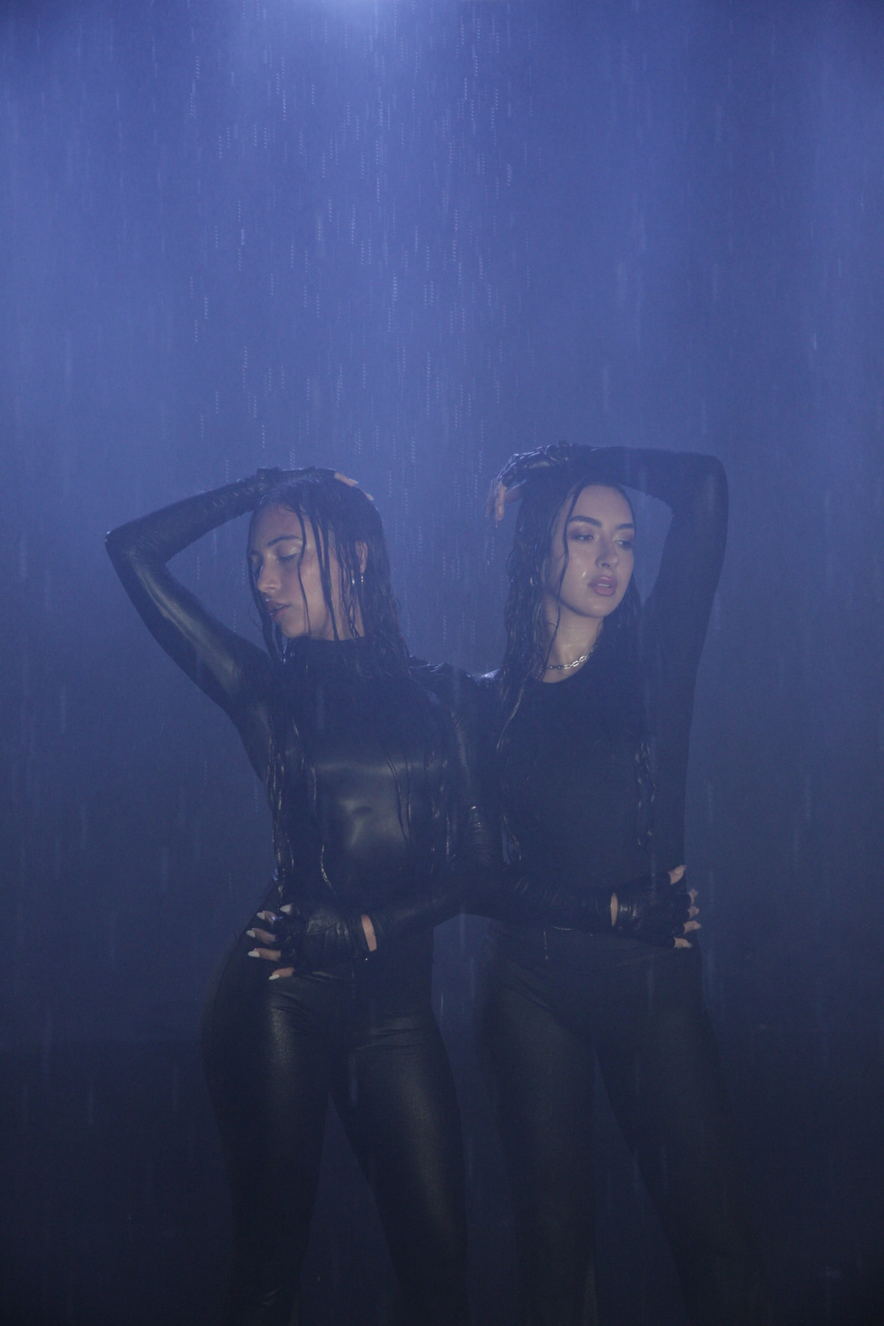 Z3LLA duo Juj Seeley and Kiana Tebyani in black outfits under blue-lit rain
